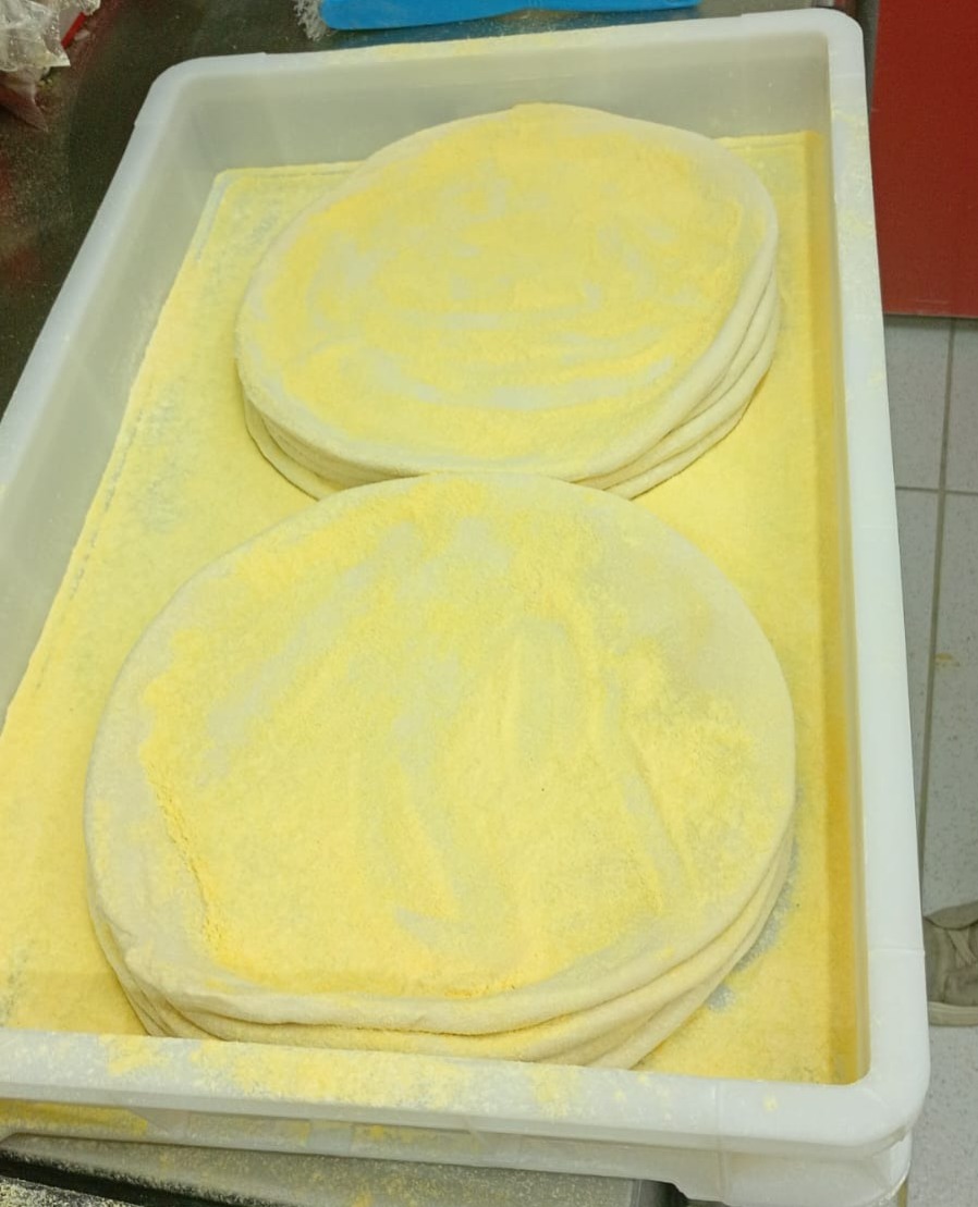 Mãos abrindo massa de pizza